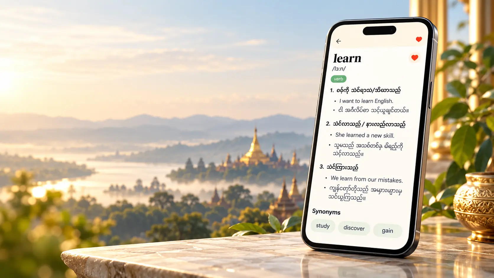 A phone displaying the English word learn with Myanmar meanings, set beside golden pagodas at sunrise